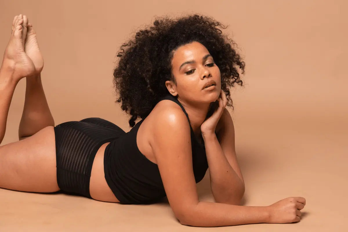 Woman with curly hair lying on the floor in black sustainable fashion attire promoting Australian Fashion Council membership.