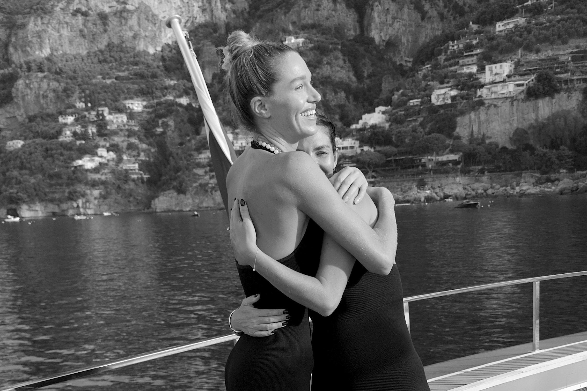 Two people embracing on a boat with a mountainous landscape in the background