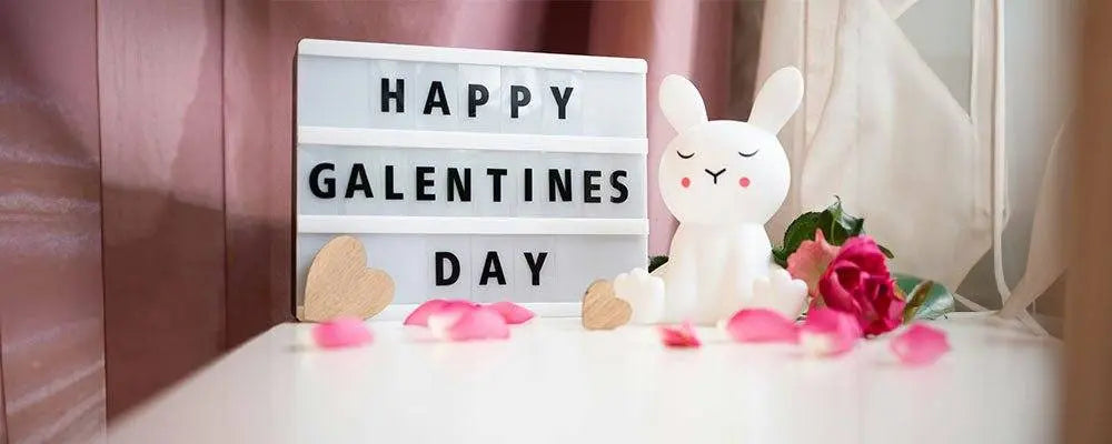 Happy Galentines Day lightbox sign with bunny figurine and pink rose petals on white table for Galentine's Day ideas celebration