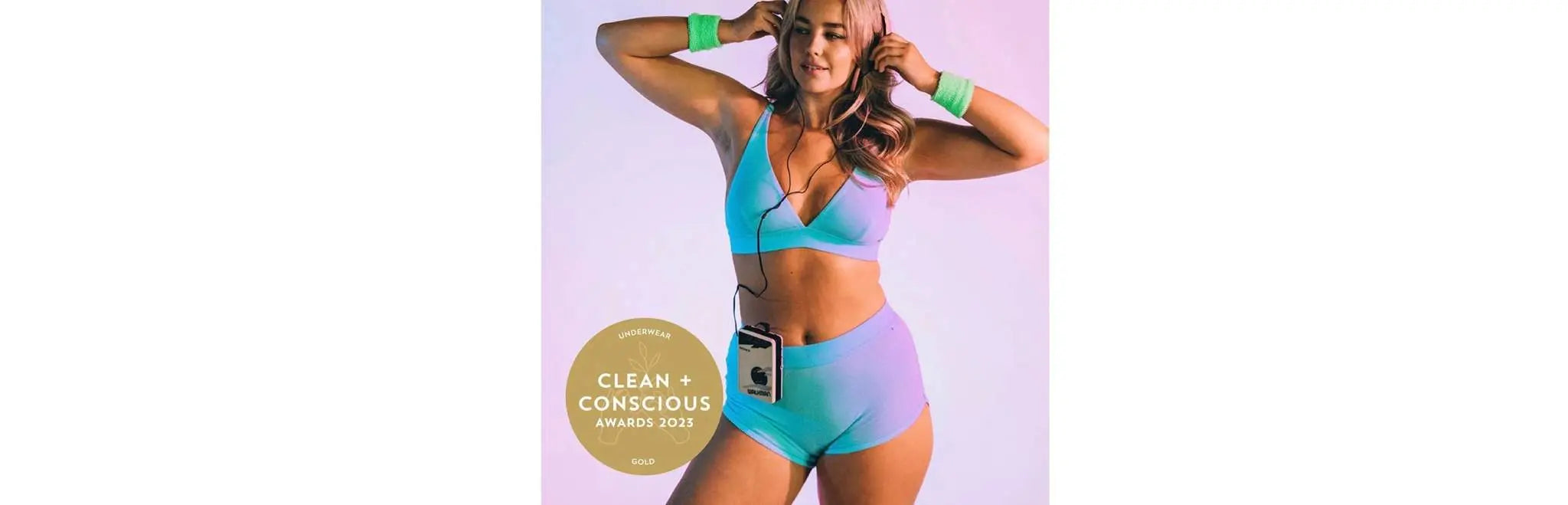 Woman in pastel blue sustainable underwear with Clean + Conscious Awards 2023 gold badge for Best Sustainable Underwear