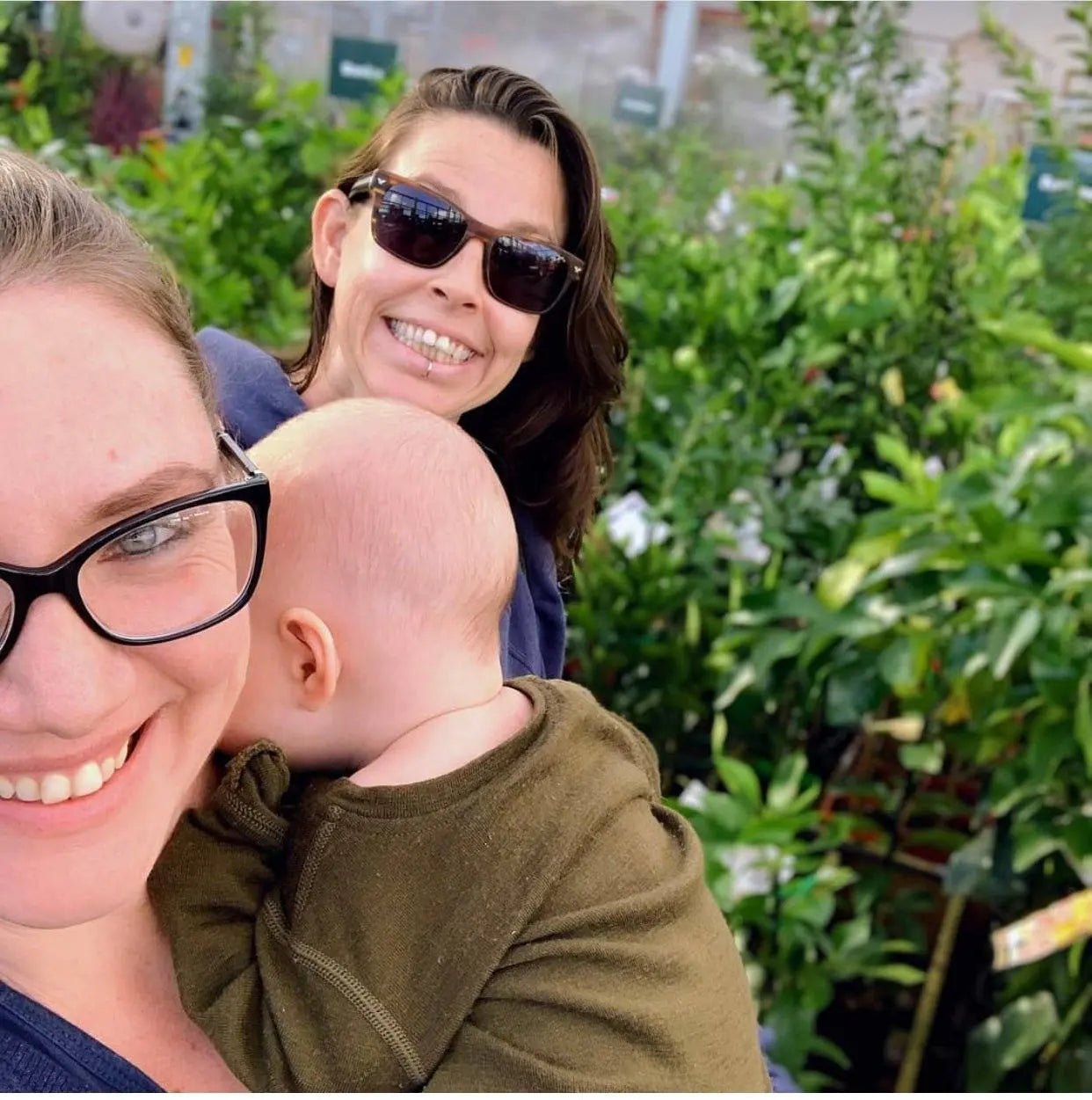 Family embracing sustainable living outdoors at a plant nursery with greenery in the background