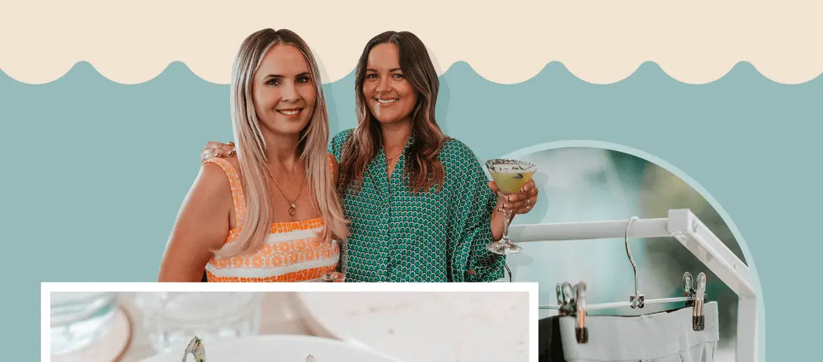 Two women smiling and holding drinks at Our Cabrini Launch Lunch with ocean views background