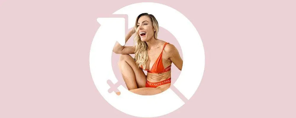 Vanessa Haldane of Journey To Worthy smiling in orange activewear with gender symbol background on pink for International Women's Day Q&A.