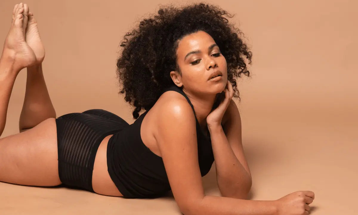 Woman with curly hair lying on the floor in black sustainable fashion attire promoting Australian Fashion Council membership.